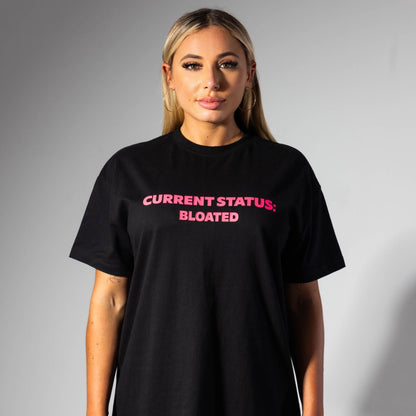 Person wearing a black t-shirt with pink text on a gray background