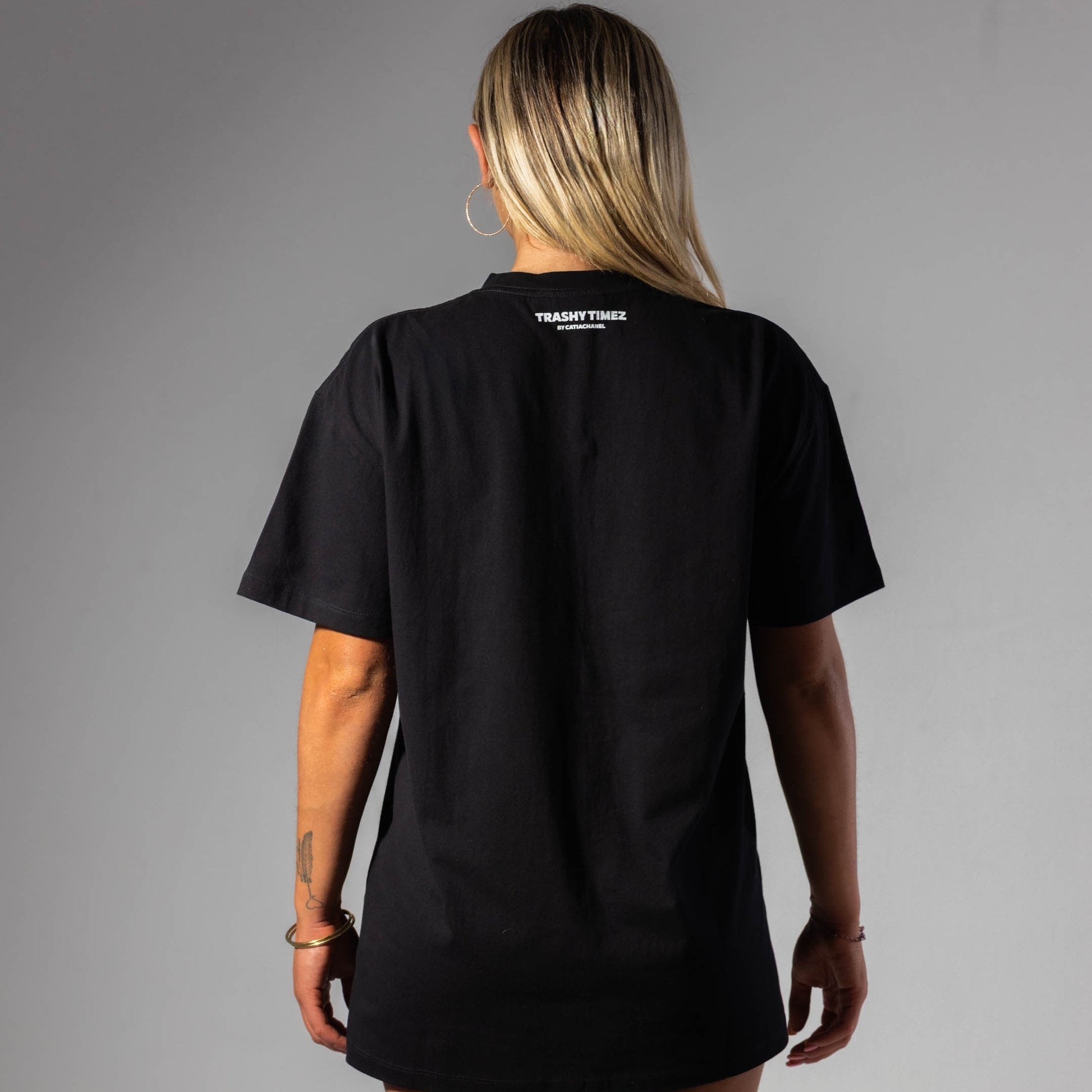 Person wearing a black t-shirt with a brand logo on the back against a gray background