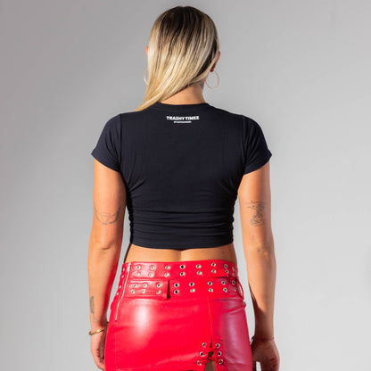 Person wearing a black crop top and red leather skirt on a gray background